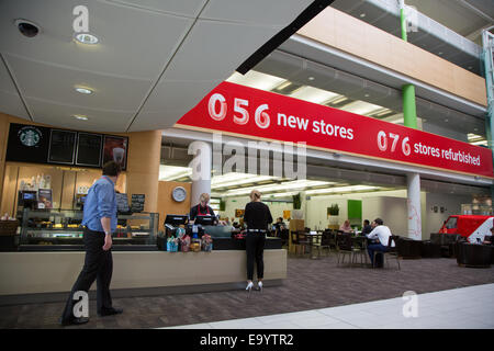 Lavoratori a bere caffè e lavorare sui dispositivi all'interno di Vodafone UK sede vicino a Newbury Foto Stock