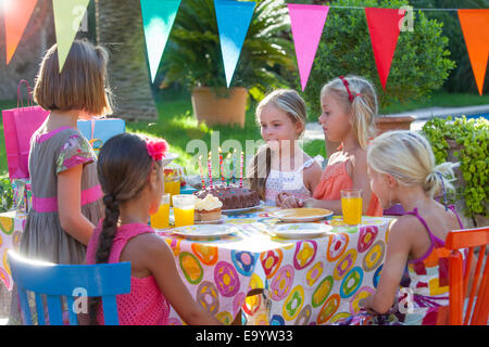 Ragazza con gli amici a tavola con la torta di compleanno Foto Stock