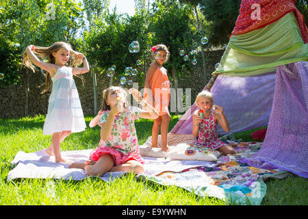 Le ragazze a soffiare bolle in summer party in giardino Foto Stock