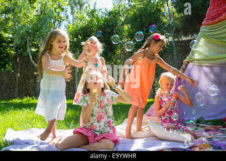 Le ragazze a soffiare bolle in summer party in giardino Foto Stock