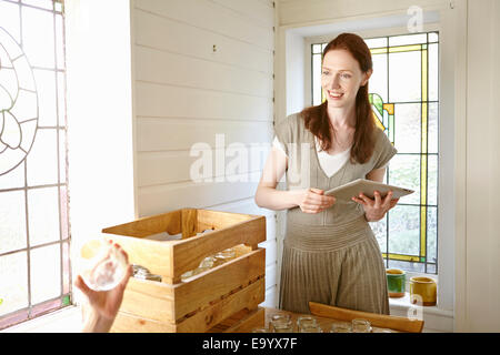 Apicoltore utilizzando digitale compressa in cucina durante la procedura di disimballaggio vasi Foto Stock