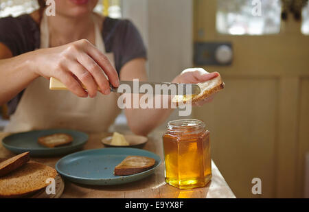 Degustazione di donna appena estratto il miele sul pane Foto Stock