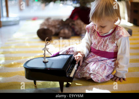 Femmina bambino seduto sul soggiorno piano giocando con Toy piano music box a Xmas Foto Stock