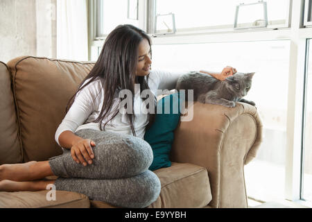 Donna stroking cat sul lettino Foto Stock