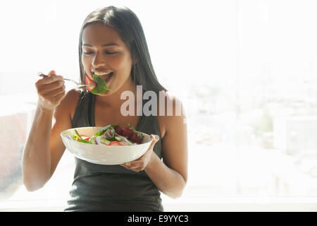 Donna insalata mangiare a casa Foto Stock