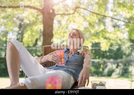 Donna matura relax nel giardino con bevanda Foto Stock