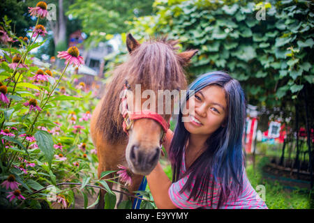 Ritratto di ragazza adolescente in piedi con pony, all'aperto Foto Stock