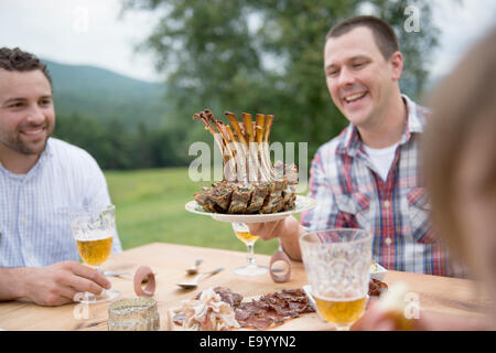 Piccolo gruppo di adulti gustando un pasto all'aperto Foto Stock