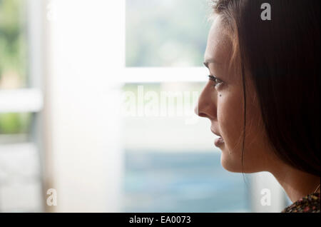 Close up ritratto di giovane donna guardando fuori della finestra Foto Stock
