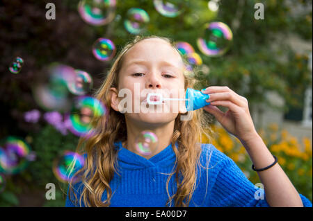 Ragazza a soffiare bolle in giardino Foto Stock