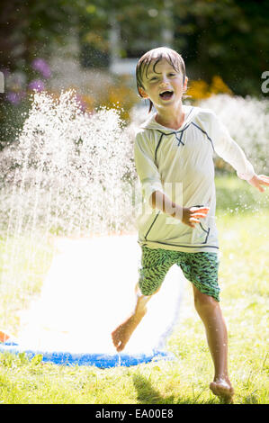 Ragazzo giocando con sprinkler da giardino Foto Stock