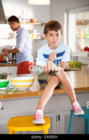 Ragazzo seduto sul banco di cucina Foto Stock