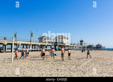 I giovani uomini a giocare a beach volley di fronte al molo nel centro cittadino di Huntington Beach, Orange County, California, Stati Uniti d'America Foto Stock