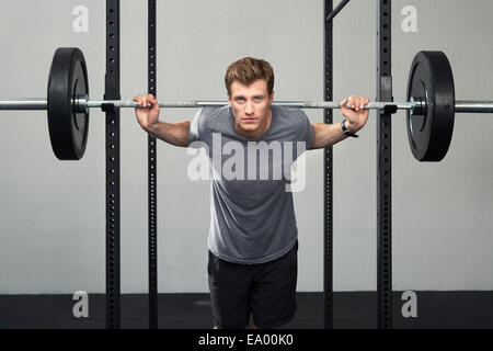 Ritratto di metà maschio adulto weightlifter sollevamento barbell in palestra Foto Stock