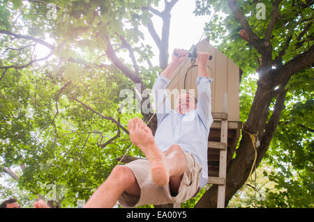 Uomo maturo lo scorrimento verso il basso sulla puleggia di albero di casa Foto Stock