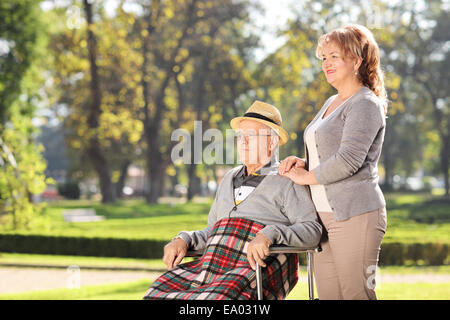 Uomo in sedia a rotelle seduto con sua moglie nel parco in una giornata di sole Foto Stock