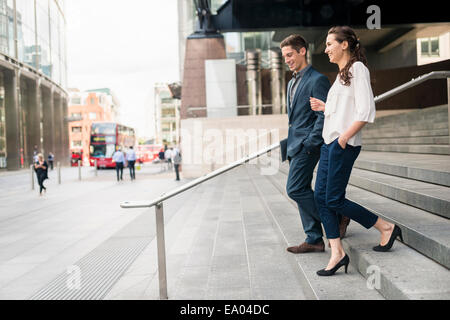 Vista posteriore del giovane imprenditore e la donna in chat mentre scendendo le scale, London, Regno Unito Foto Stock