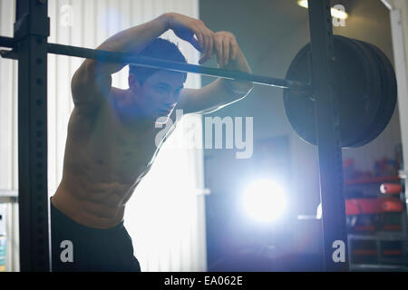 Uomo appoggiato su barbells in palestra Foto Stock