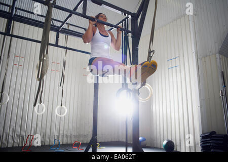 Donna facendo chin ups in palestra Foto Stock