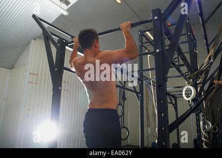 L'uomo facendo di pull up in palestra Foto Stock