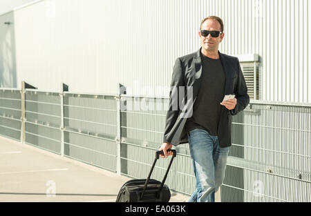 Uomo maturo tirando la valigia su ruote Foto Stock