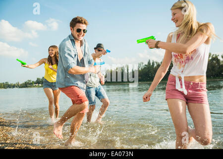 Amici a giocare con le pistole ad acqua nel lago Foto Stock