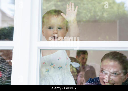 Bambina e madre guardando fuori della finestra Foto Stock