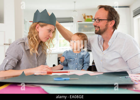 Famiglia rendendo corone di carta Foto Stock