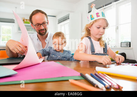 Famiglia rendendo corone di carta Foto Stock