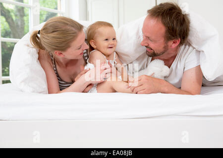 I genitori a giocare con la nostra bambina sotto piumone Foto Stock