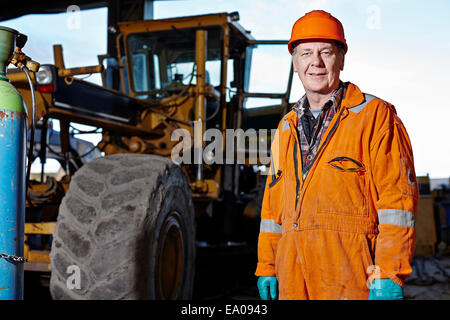 Ritratto di quarry lavoratore accanto all'escavatore sito di cava Foto Stock