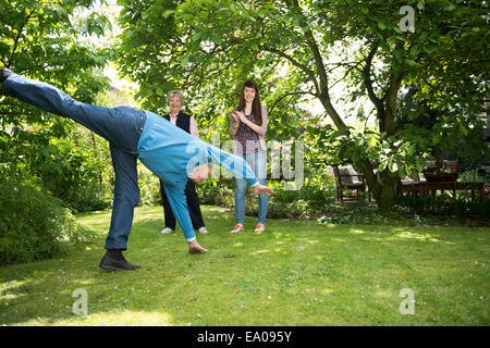 Nonni e nipote facendo acrobazie in giardino Foto Stock