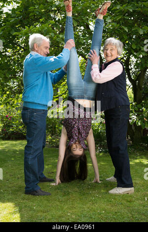 Nonni e nipote facendo acrobazie in giardino Foto Stock