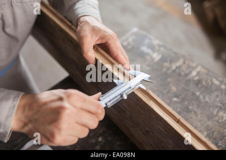 Carpenter la misurazione asse di legno con un calibro a corsoio in fabbrica, Jiangsu, Cina Foto Stock