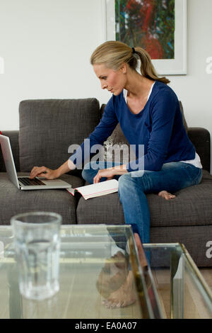 Donna matura che lavorano da casa su computer portatile Foto Stock