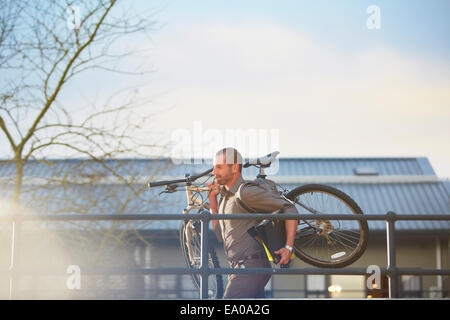 Imprenditore in esecuzione con la bicicletta e la cartella in armi Foto Stock