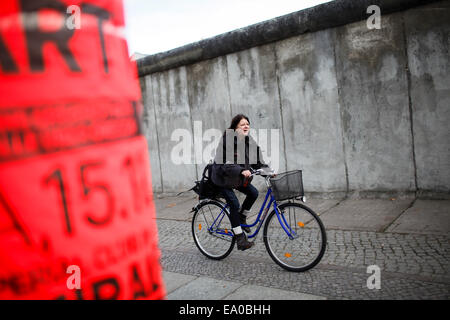 Berlino, Germania. 4 Novembre, 2014. La donna corse in bicicletta lungo un muro di Berlino a bordo di un Memoriale del Muro di Berlino sito a Berlino, Germania, il 9 novembre 4, 2014. La Germania sarebbe commemorare il venticinquesimo anniversario della caduta del muro di Berlino la domenica, nov. 9. © Zhang ventola/Xinhua/Alamy Live News Foto Stock