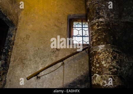 Finestra medievale con telaio in legno e ferro reticolo in Praga. Antiche mura in pietra, corrimano in legno su grande scala Foto Stock