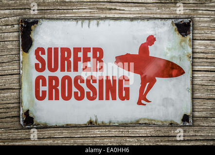 Retrò Surfer Crossing segno di avvertimento su sfondo di legno Foto Stock