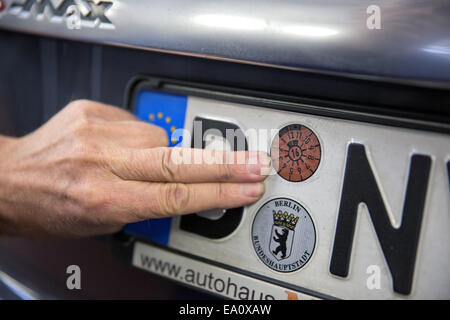 Berlino, Germania. 4 Novembre, 2014. Un membro dello staff del TUV, ispezione tecnica associazione per le automobili e i prodotti di consumo, attribuisce un TUV adesivo di validazione di una vettura dopo un controllo approfondito presso il test TUV e la stazione di servizio a Berlino, Germania, 4 novembre 2014. Foto: Joerg Carstensen/dpa/Alamy Live News Foto Stock