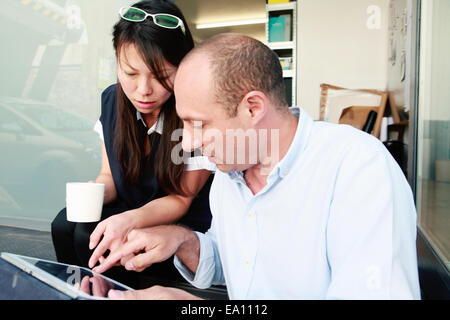 Maschio e femmina architetti guardando digitale compressa in office Foto Stock