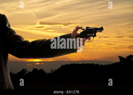 Silhoutte di un uomo con una pistola al tramonto Foto Stock