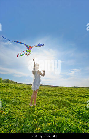 Giovane donna volare un aquilone nel campo Foto Stock