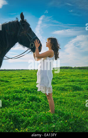 Giovane donna petting cavallo in campo Foto Stock