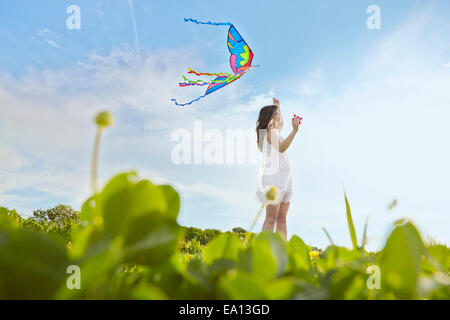 Livello di superficie vista della giovane donna volare un aquilone nel campo Foto Stock