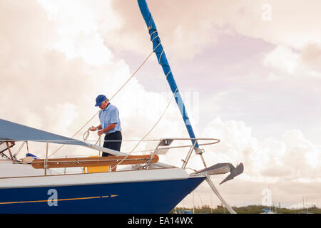 Uomo Senior controllo corde sulla barca a vela Foto Stock