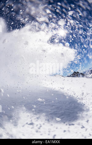 Motion shot di polvere di neve con sunrise e cielo blu su sfondo Foto Stock