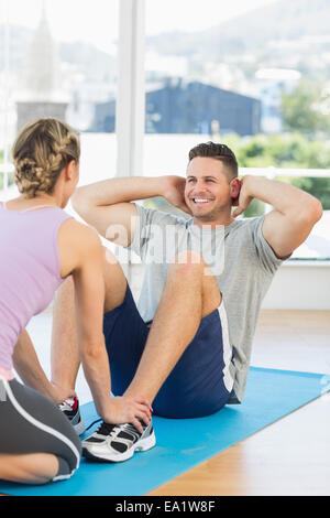 Il Trainer assiste montare l uomo nel fare si siede fino Foto Stock