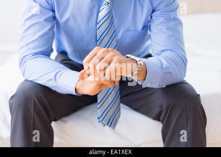 Imprenditore seduta sul letto controllando il tempo Foto Stock