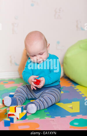 Carino piccolo bambino gioca con i giocattoli colorati a casa Foto Stock